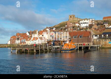 Whitby, costa dello Yorkshire - vista sui cottage dei pescatori e la stazione dei bagnini sotto la chiesa di St Mary sull'East Cliff Foto Stock