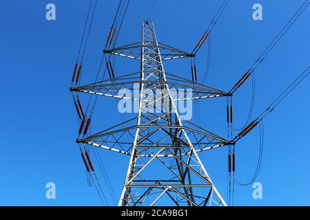 Grande, pilone elettrico in metallo (torre di trasmissione) vista dal suolo con cielo blu a Manchester, Inghilterra Foto Stock