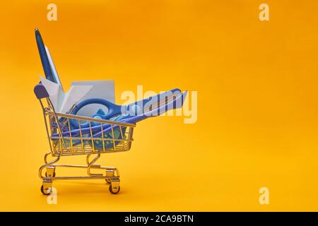 minimalismo carrello e cancelleria su sfondo giallo, scuola, università, spazio di copia Foto Stock