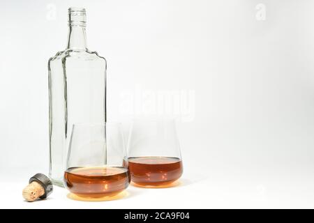 Flacone vuoto con tappo e due bicchieri riempiti Foto Stock