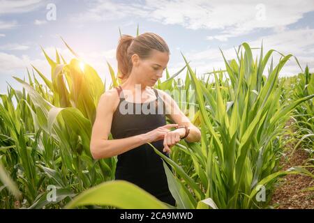 donna sportiva che usa un orologio intelligente all'aperto in campagna, concetto di fitness all'aperto. Foto Stock