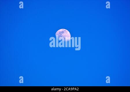 Una bella luna con i suoi crateri può essere vista nel cielo chiaro di giorno. Il lato illuminato dal sole è chiaramente visibile. Foto Stock