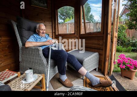 Coppie anziane negli anni 80 che si godono il caldo clima estivo nella loro casa estiva giardino, Inghilterra, Regno Unito Foto Stock