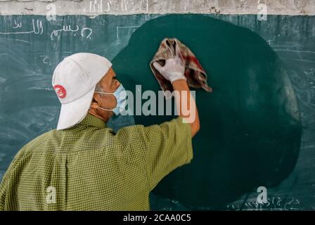 Gaza, Palestina. 05 agosto 2020. Un lavoratore indossa una maschera facciale e guanti mentre sanitizza una scuola prima che inizi il nuovo anno scolastico, tra le preoccupazioni della diffusione del coronavirus (Covid-19) a Khan Yunis. Credit: SOPA Images Limited/Alamy Live News Foto Stock