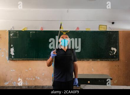 Gaza, Palestina. 05 agosto 2020. Un lavoratore indossa una maschera facciale e guanti mentre sanitizza una scuola prima che inizi il nuovo anno scolastico, tra le preoccupazioni della diffusione del coronavirus (Covid-19) a Khan Yunis. Credit: SOPA Images Limited/Alamy Live News Foto Stock