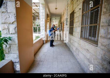 Gaza, Palestina. 05 agosto 2020. Un lavoratore indossa una maschera facciale e guanti mentre sanitizza una scuola prima che inizi il nuovo anno scolastico, tra le preoccupazioni della diffusione del coronavirus (Covid-19) a Khan Yunis. Credit: SOPA Images Limited/Alamy Live News Foto Stock