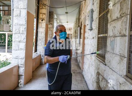 Gaza, Palestina. 05 agosto 2020. Un lavoratore indossa una maschera facciale e guanti mentre sanitizza una scuola prima che inizi il nuovo anno scolastico, tra le preoccupazioni della diffusione del coronavirus (Covid-19) a Khan Yunis. Credit: SOPA Images Limited/Alamy Live News Foto Stock