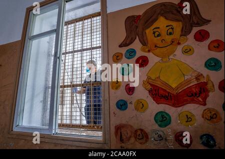 Gaza, Palestina. 05 agosto 2020. Un lavoratore indossa una maschera facciale e guanti mentre sanitizza una scuola prima che inizi il nuovo anno scolastico, tra le preoccupazioni della diffusione del coronavirus (Covid-19) a Khan Yunis. Credit: SOPA Images Limited/Alamy Live News Foto Stock