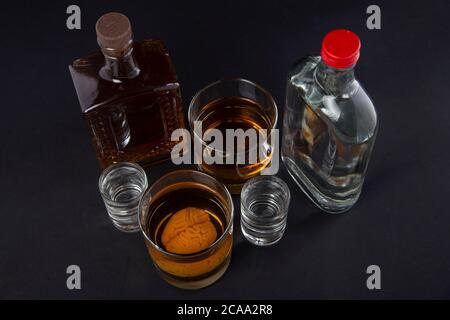 cervello umano in un bicchiere con bevanda alcolica, sullo sfondo di bottiglie con alcol. Dipendenza da alcol. Danno al cervello da alcool Foto Stock