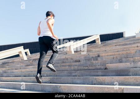 vista posteriore di un sportivo che saliva una scala durante il suo allenamento, concetto di sport urbano e stile di vita sano, spazio di copia per il testo Foto Stock