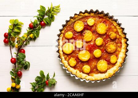 Torta aperta di pasta frolla con prugna di ciliegia, clafoutis di prugna mirobalana su sfondo bianco Foto Stock