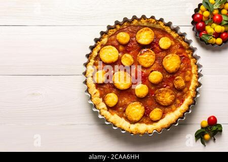 Torta aperta di pasta frolla con prugna di ciliegia, clafoutis di prugna mirobalana su sfondo bianco Foto Stock