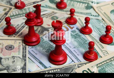 Visualizza su carta pile di denaro US banconote in dollari con pezzi scacchi rossi di gruppo (fuoco sul re di fronte) Foto Stock