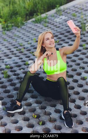 Bella giovane istruttore di yoga femminile che conduce una classe online. Giovane donna che pratica yoga con il suo telefono cellulare. Foto Stock