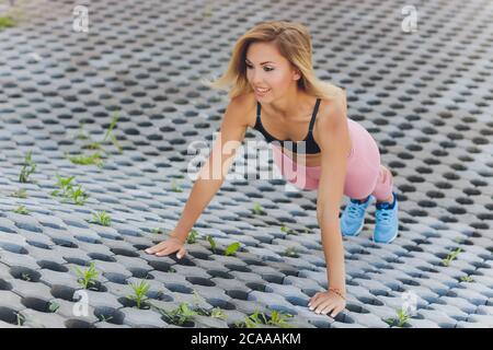 Donna attraente e forte che stretching prima di fitness nel parco estivo. Concetto sportivo. Stile di vita sano. Foto Stock