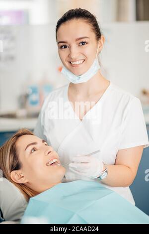 ritratto di dentista femminile in uniforme del medico bianco in piedi in ufficio vicino all'attrezzatura e guardare la macchina fotografica. Medicina, dentista, concetto ortodontico Foto Stock
