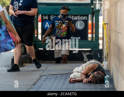 La gente che esce dalla metropolitana passa un individuo senza dimora che dorme sul marciapiede a Chelsea a New York sabato 1 agosto 2020. (© Richard B. Levine) Foto Stock