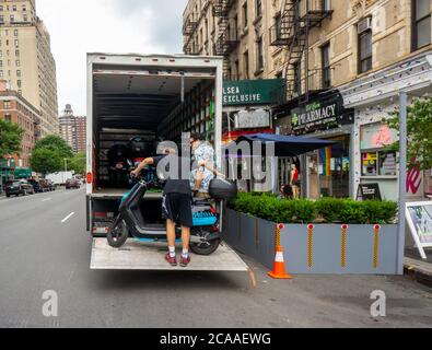 I lavoratori della compagnia di condivisione del ciclomotore Revel rimuovono il loro inventario dalle strade, visto nel quartiere Chelsea di New York venerdì 31 luglio 2020. Dopo diverse morti Revel ha annunciato che sta temporaneamente chiudendo le sue attività a New York fino a quando non rafforzano i protocolli di sicurezza e responsabilità dei piloti. (© Richard B. Levine) Foto Stock