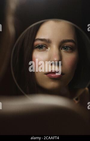 Giovane donna attraente che guarda il riflesso di sé nello specchio. Foto Stock