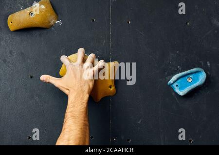 Scalatore s maschio mani coperte con polvere di magnesio, afferrando le maniglie colorate nel corso arrampicata indoor allenamento Foto Stock