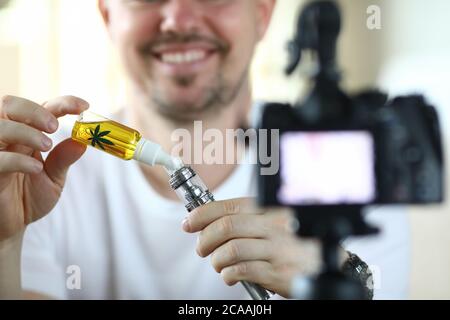Il ragazzo di fronte alla fotocamera riempie un vape Foto Stock