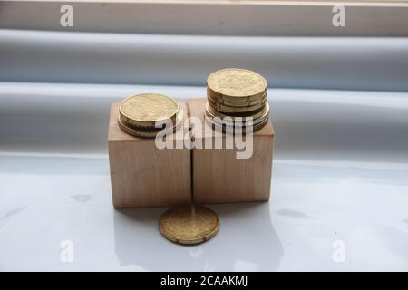 Cubetti di legno con monete messi in pile. Concetto di risparmio aziendale o personale. Foto Stock