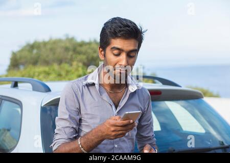 L'indiano scettico frustrato ha sorpreso l'uomo triste che controlla guardando il telefono testando, denominando il concessionario dopo un guasto dell'automobile Foto Stock