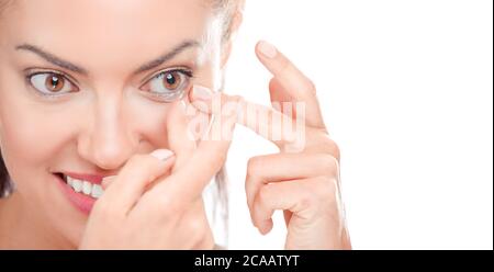 Lente a contatto per la visione. Primo piano del viso femminile con l'applicazione della lente di contatto sui suoi occhi marrone nocciolo. Bella donna che mette gli obiettivi degli occhi con le mani. Opz Foto Stock