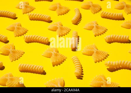 Pasta arricciata non cotta su fondo giallo. Tradizionale modello di maccheroni crudi asciutti. Nessuno Foto Stock
