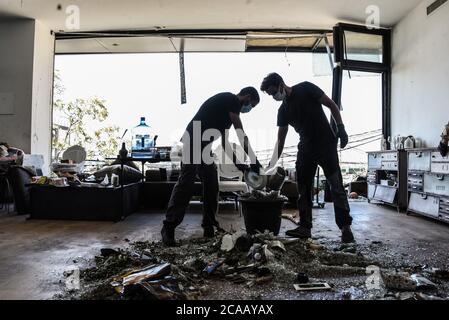 Beirut, Libano, 5 agosto 2020. Le persone lavorano per eliminare i detriti dal loro appartamento direttamente di fronte al porto della capitale, luogo di una catastrofica esplosione che ha distrutto gran parte dei quartieri settentrionali della città. Elizabeth Fitt Foto Stock