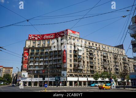 Bucarest, Romania - 28 giugno 2020: Un grande logo della casa produttrice di bibite Coca-Cola è esposto sulla sommità di un blocco di appartamenti, a Piata Roma Foto Stock