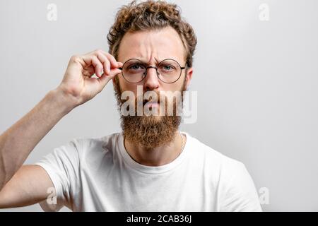 Headshot di seri bearded ners, scienziato, con baffi e barba, indossa occhiali rotondi, ha capelli alla moda, guarda con sicurezza. Foto Stock