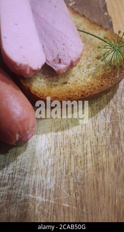 primo piano di toast con salsicce e aneto su una tavola di legno Foto Stock