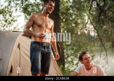 due ragazzi piacevoli sono felici perché hanno una vacanza fantastica nella splendida foresta con il fiume. concetto di ridere e divertimento. vista ad angolo basso Foto Stock