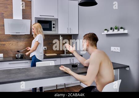 uomo disgraziato indignato per sua moglie in cucina, infelice coppia sposata discutere ogni giorno, hanno crisi in famiglia. l'uomo arrabbiato non ha ottenuto abbastanza Foto Stock