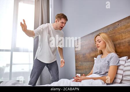 marito isterico esprime malcontento, moglie non si preoccupano, sedersi a letto non avendo emozioni, è emotivamente devastata Foto Stock