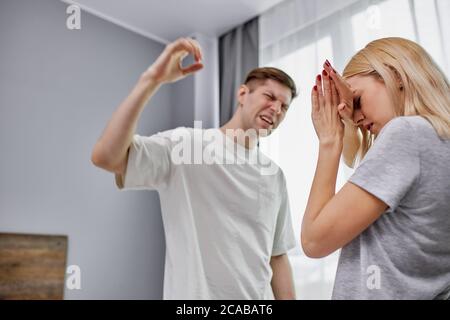 l'uomo mentalmente squilibrato batte la moglie a casa, la donna indifesa cerca di proteggersi, difendersi Foto Stock