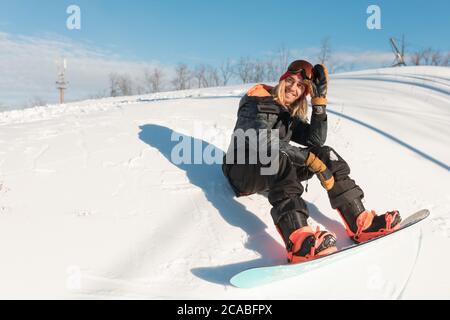 un ragazzo bello e positivo che si è preso una pausa dopo lo snowboard. buon fine settimana all'aria fresca. foto a lunghezza intera. spazio copia Foto Stock