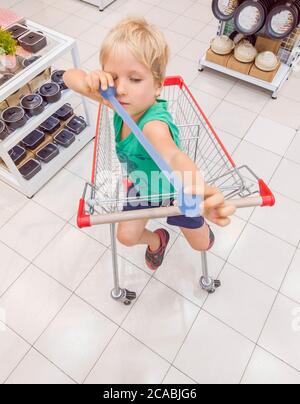 Felice bambino sorridente seduto nel carrello del carrello che si diverte Foto Stock