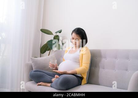 Giovane donna incinta prendendo medicine Foto Stock