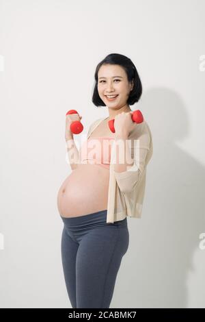 Donna incinta asiatica fare esercizio, in piedi e sollevando dumbbells, concetto di maternità di gravidanza sportiva Foto Stock