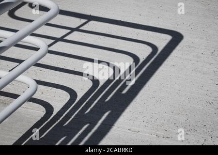 Ombra di una recinzione bianca sulla terra cimente. Foto Stock