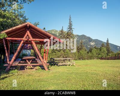 Tavolo e panca in legno con tetto in chalet Diham con i Monti Bucegi sullo sfondo. Foto Stock