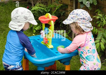 Immagine autentica dei bimbi bimbi piccoli che giocano in acqua con i giocattoli all'aperto in un giardino d'estate. Inghilterra Gran Bretagna Foto Stock