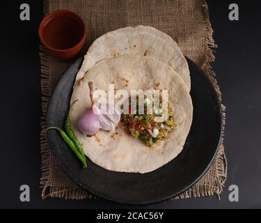 Baigan/Baingan Bharta - purè di melanzane arrosto cotte con spezie e verdure. Servito con pane piatto di farina di Jowar conosciuto come bhakar/bhakri. Foto Stock