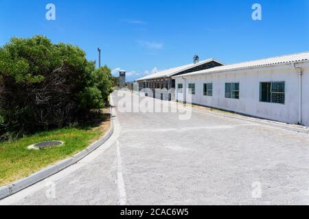 Robben Island, Sudafrica - 24 novembre 2019: Guardando giù gli edifici delle carceri verso una torre di guardia alla fine di una strada acciottolata Foto Stock