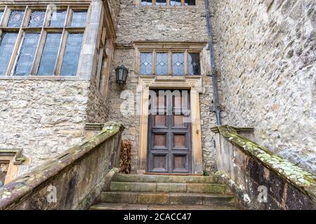Vecchio ingresso porta in legno con scalini in pietra e bifore. Foto Stock
