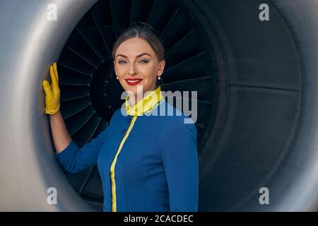 Felice giovane stewardess posa per la fotocamera Foto Stock