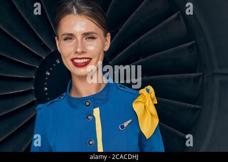 Felice giovane assistente di volo caucasico che guarda avanti Foto Stock
