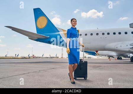 Dipendente della compagnia aerea in piedi con il bagaglio presso l'aeroporto Foto Stock